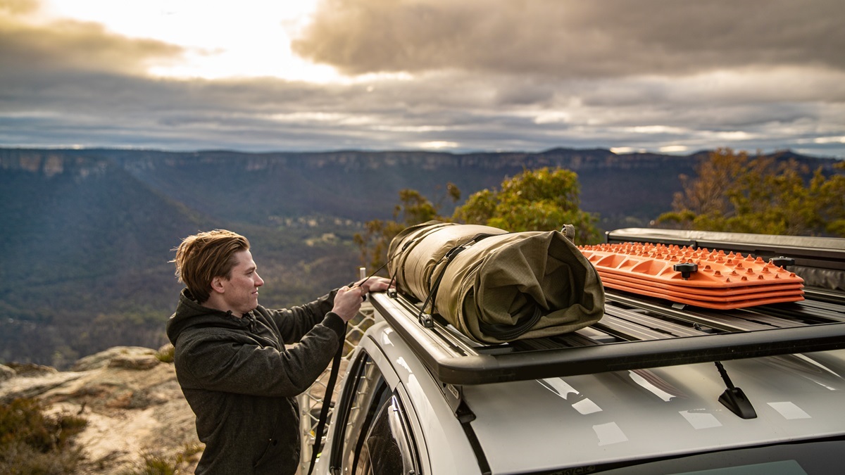 A man putting his camping gear on his roof rack
